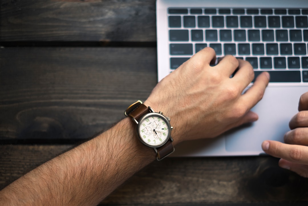 Freelancer using a laptop and smartphone to track time with a timer app on desk
